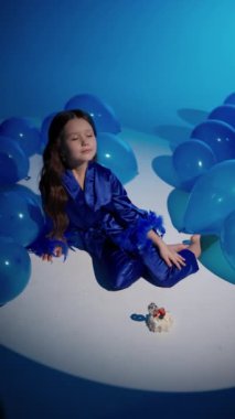 Şenlik balonlarının arka planında saten mavi takım elbiseli çocuk.