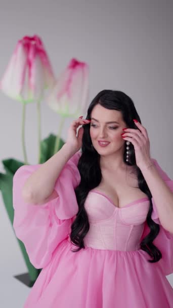 Model Dark Hair Shiny Pink Dress Adjusts Earrings Background Abstract — Vídeo de Stock