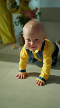 Küçük çocuk, Ukrayna süsüsüyle parlak sarı gömleği içinde yerde sürünüyor ve mutlu..