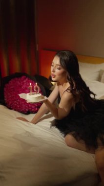 Kadın dilek diliyor, doğum günü pastasına mum üflüyor ve onu mum ışığı ve parlak güllerle dolu bir odaya sarıyor..