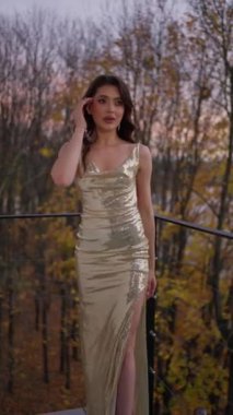 Woman in chic dress with sequins on background of autumn leaves.