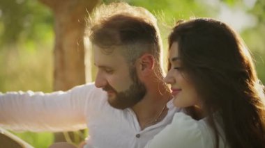 Erkek ve kadın sarılıyor, mutlu ve rahat, yaprakların arka planında.
