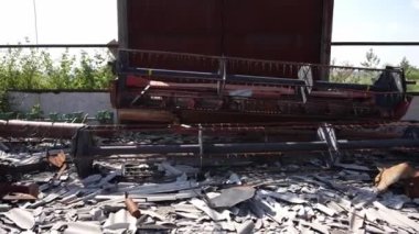 Yıkılmış çatı altında tarımsal makinelerin kalıntıları. Metal çatının altında hasar görmüş ekipman ve makineler.