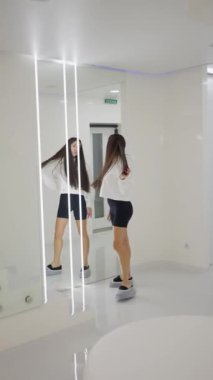 Amaçlı adımlarla, kadın parlak, şık güzellik salonunun minimalist merdivenlerine tırmanıyor, yansıma hareketi.