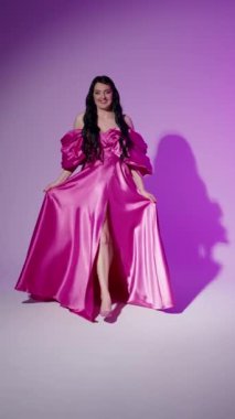 Pembe elbiseli seksi genç kadın fotoğrafçıya seksi poz veriyor.