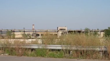 Betonun içinde büyüyen bitki örtüsü olan terk edilmiş bir sanayi tesisi. Terk edilmiş binaları ve aşırı gelişmiş alanları olan boş bir fabrika..