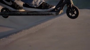 Genç bir adam şehir caddesi boyunca scooter sürüyor..
