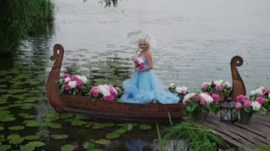 Kraliyet elbiseli kadın çiçeklerle süslenmiş bir teknede yelken açıyor..