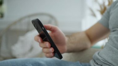 Rahat ev ortamında, yakın çekim modern akıllı telefonla el ele tutuşmayı tasvir ediyor, bağlantı ve günlük teknoloji kullanımını öneriyor.