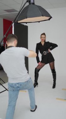 Moda çekimi sahnesi, fotoğrafçı merceğe odaklanırken stüdyo ışıklarının altında kendine güveni yüksek bir poz veriyor..