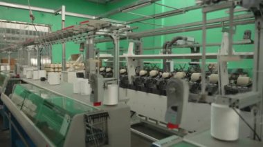 Üretim makineleri ve iplik makaraları olan tekstil fabrikasının iç görünümü. Modern ekipman ve teknolojiler tekstil ürünlerinin üretimi için kullanılır..