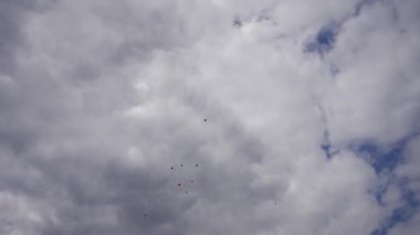 Mavi gökyüzünde kabarık küreler arasında parlak toplar.