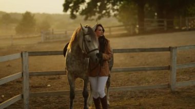 Mutlu genç bir kadın kumsalda atını okşuyor..