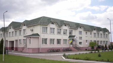 Yeşil çatılı ve krem renkli duvarları olan iki katlı eğitim binasının birçok penceresi ve biri Ukrayna bayrağı ile süslenmiş iki küçük girişi var. Bisikletler ön cephe boyunca park edilmiş..