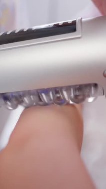 Deride kullanılan kozmetik alet. Resim, cihazın pürüzsüz metal yüzeyini ve deriyle temas eden şeffaf silindirleri vurgular.