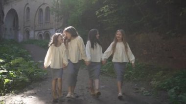 Açık renk bluz ve gri etekli bir grup genç kız antik şatonun etrafında mutlu bir şekilde yürüyorlar..