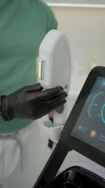 Profesyonel eldivenler tarafından işletilen estetik lazer cilt tedavi cihazının yakın çekimi.