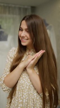 Uzun kahverengi saçlı neşeli genç bir kadın sıcacık gülümsüyor, elleri nazikçe birbirine yapışıyordu..