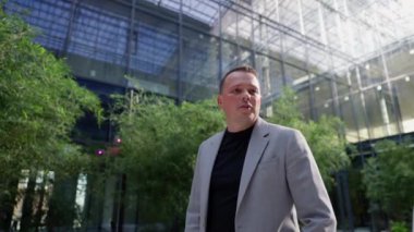 Kapalı ofis bahçesinin doğal güzelliği ile çevrili, etkin bir şekilde sohbet eden iş adamının dinamik anı. Kafasında karmaşık cam yapılar var..