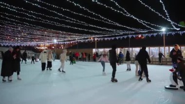 Geceleri, her yaştan insanın festival ışıkları altında etkinliğin tadını çıkardığı canlı açık hava buz pateni pisti..