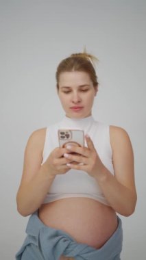 Müstakbel anne telefonunu kullanıyor, belki anılarını paylaşıyor ya da yakalıyor, teknoloji ve hamilelik yolculuğunun kesişimlerini somutlaştırıyor..