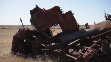Eski makinelerin paslanmış, çürüyen kalıntıları açık mavi bir gökyüzünün altında kuru bir tarlada yatıyor..