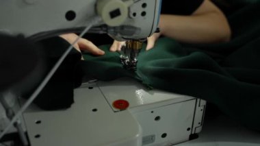 Profesyonel Terzi Başlıklı Kız Spor Kazağına Bağlanıyor. Kazağa ek olarak dikiş makinesiyle kaputu manevra yapan yetenekli eller..