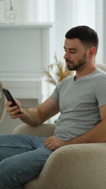 Rahat bir insan, rahat bir evde telefonla göz gezdirir. Adam rahat bir şekilde kanepede oturuyor, akıllı telefonuna dalmış..