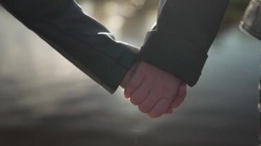 Yumuşak güneş ışığıyla aydınlanan iki çocuğun el ele tutuşması sakin ve hassas bir an yaratıyor..