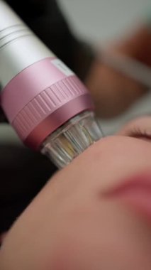 Cilde uygulanan pembe ve gümüş bir güzellik aleti kullanılarak yapılan bir cilt bakımı.