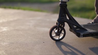 Pürüzsüz kaldırımda siyah scooter tekerleğinin yakın çekimi. Kaykay parkındaki scooter 'ın ayrıntıları.