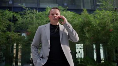 Ofisteki telefon görüşmelerine dalmış bir işadamı, iş ve barış dengesini vurguluyor.