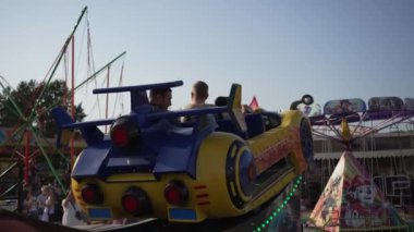 Renkli bir lunapark gezisi. Araba şeklinde. Binicisi de eğlenceli atmosferin tadını çıkarıyor..