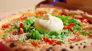 Peynirle kaplı pizza, roka, güneşte kurutulmuş domates, altın kabuklu parmesan..