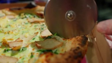 Eritilmiş peynirli tavuk pizzası, ıspanak ve pizza bıçağıyla dilimlenen altın hamuru..