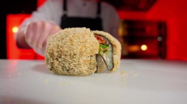 Somon, avokado, krem peynir ve bıçakla dilimlenmiş pirinçli suşi rulosu..