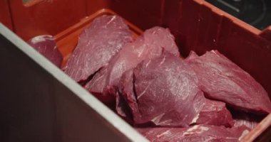 Bir tesisteki yemek hazırlığını vurgulamak için kırmızı plastik bir kaba birkaç çiğ et kesimi konur..