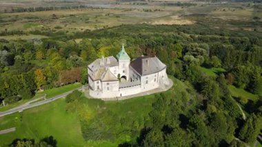 Yeşillik ve açık araziyle çevrili tarihi bir şatonun havadan görünüşü.