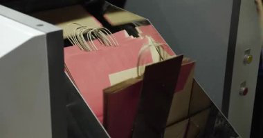 Yapım atölyesindeki üretim hattında bükümlü saplı kağıt poşetler yapmak..