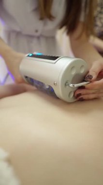 Profesyonel bir güzellik aleti kullanarak hastalara cilt tedavisi uygulayan bir terapistin yakın çekimi..