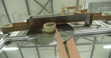 Bir fabrika ortamında metal parçaları, sicimler ve dairesel bileşenlerin yer aldığı endüstriyel bir makinenin yakın çekim görüntüsü.