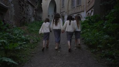 Aynı kıyafetleri giyen beş kız grubu eski tuğla harabelerin yanında el ele yürüyorlar. Tarihi doğal ortamda birlik ve dostluk..
