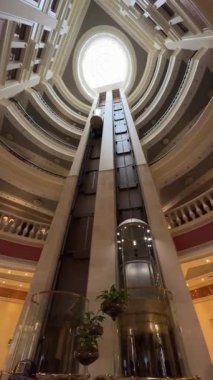 Panoramik cam asansörlü, tavan penceresi tavanlı, modern mimari ve zarif tasarım unsurları olan lüks otel avlusunun iç manzarası..