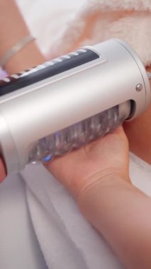 Güzellik salonundaki endermoloji paten cihazını kullanarak el masajı, estetik terapistin cilt yenilenmesi için modern LPG makinesiyle el tedavisi uygulaması..