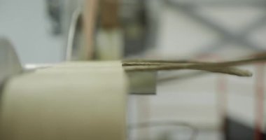 Endüstriyel makine işleme kartonunun hassas bıçaklarla yakın çekimi. Fabrika ayarlarındaki karton kenar kesimi, sığ odak içindeki otomatikleştirilmiş üretim detaylarını gösteriyor.