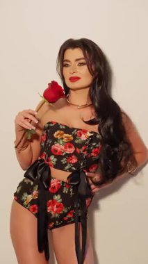 Çiçekli güzel bir kadın elinde kırmızı bir gül, zarif bir model, kendine güvenen bir ifade ve uzun saçlı..