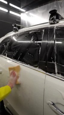 Kapalı araba yıkamada sünger ve sabunla el yıkama, detaylı dış oto bakım servisi sırasında eldivenli kişinin cam ve kapısını kapatma..