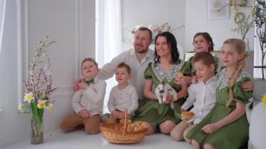 Mutlu aile tavşan ve piliçlerle poz veriyor, parlak dekore edilmiş odada grup portresi yapıyor ya da Paskalyayı yeşil elbiseli ve beyaz gömlekli çocuklarla kutluyor..