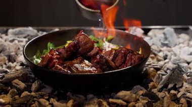 Kömürlerin üzerinde sıcak dökme demir tavada servis edilen taze otlar ve sebzelerle ızgara et, renkli garnitürlü sulu ızgara kaburga ve bir restorana dökülen sos..