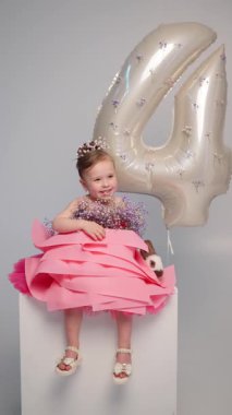 Pembe elbiseli, tavşanlı ve çiçekli sevimli kız, 4. doğum gününü balonla ve stüdyoda şenlikli aksesuarlarla kutlayan çocuk..